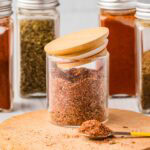 Homemade fajita seasoning in a glass container with the jar slightly on.