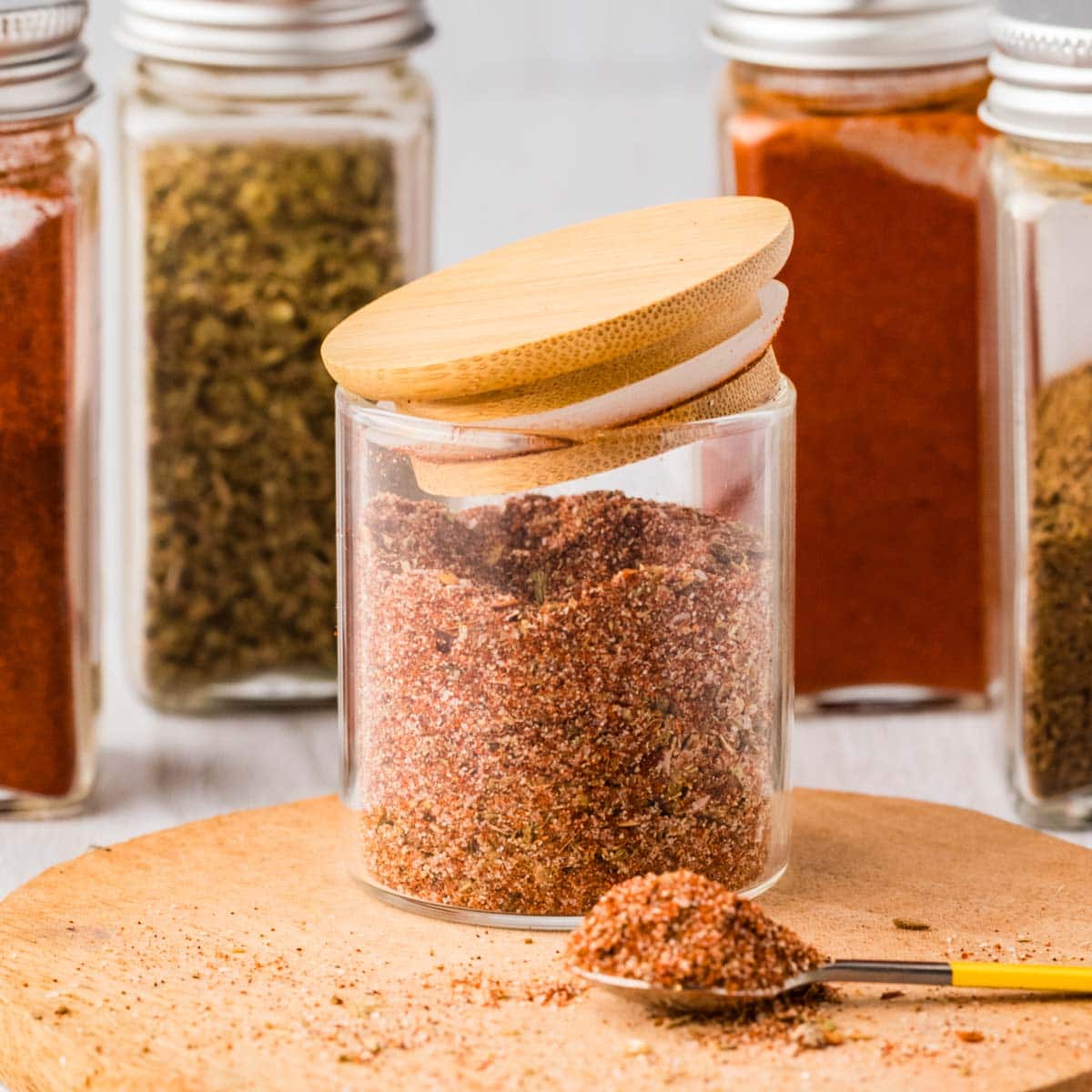 Homemade fajita seasoning in a glass container with the jar slightly on.