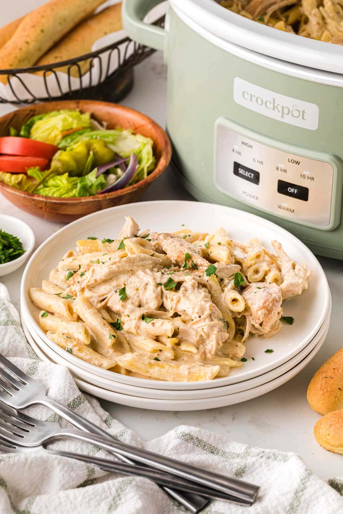 Olive garden chicken pasta on a plate with a crockpot in the background.