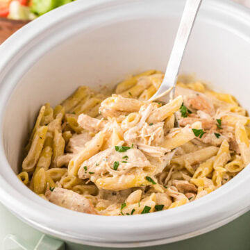 A ladle scooping out of serving of Italian chicken pasta.