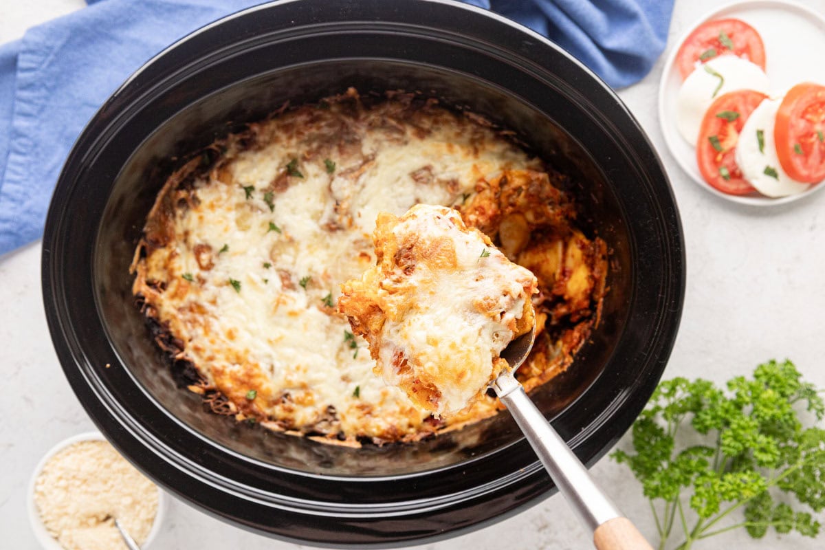 Scooping out a serving of ravioli lasagna from the slow cooker.