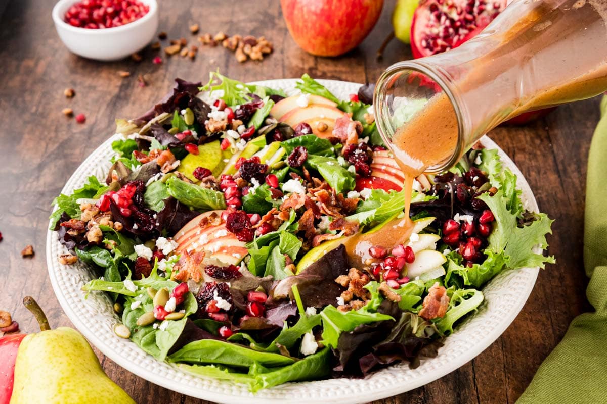 Pouring the apple vinaigrette onto the pear, apple and feta salad.