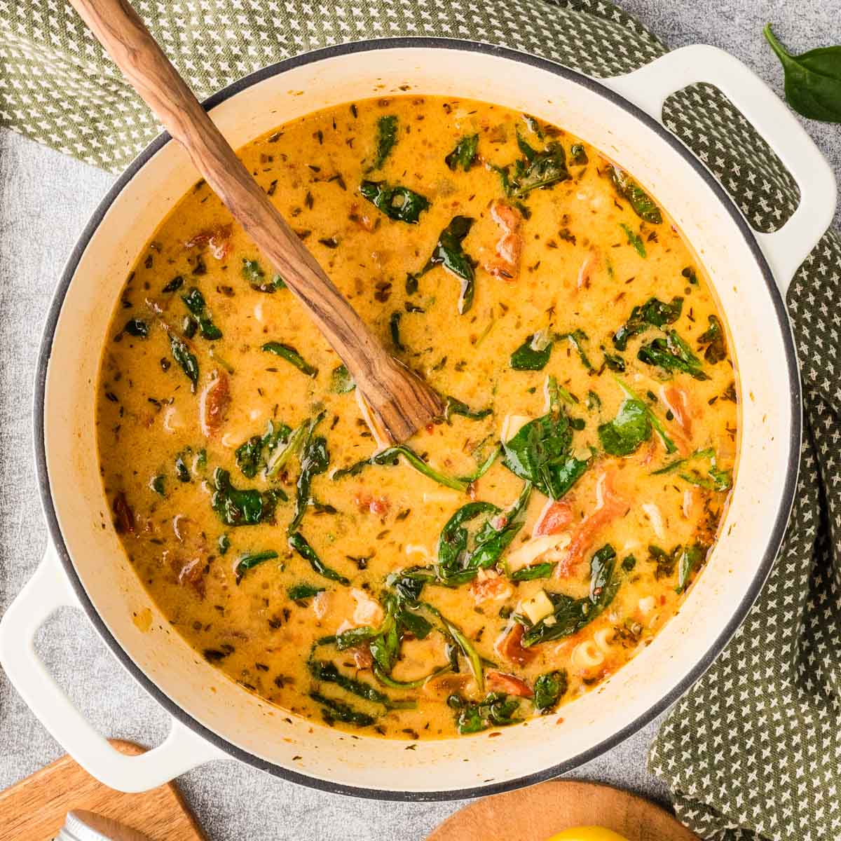 Overhead shot of a large pot of marry me chicken soup with a wooden spoon.