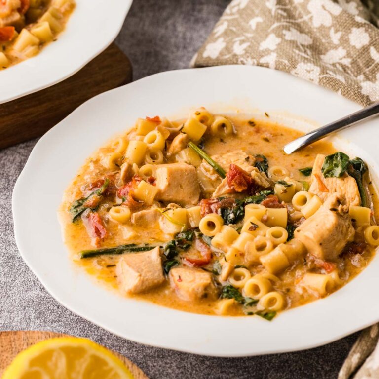 Marry me chicken soup served in a white bowl with a spoon.