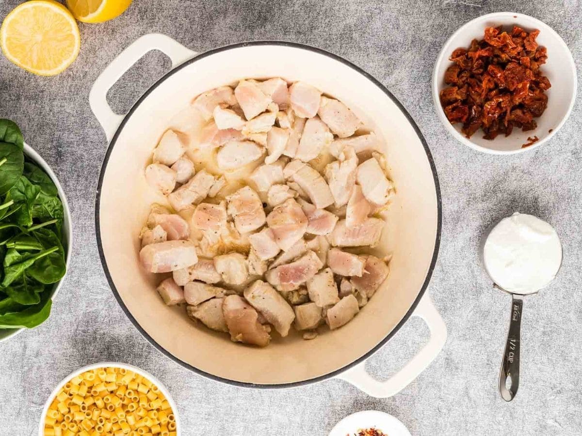 Searing the chicken cubes in a large Dutch oven pot.
