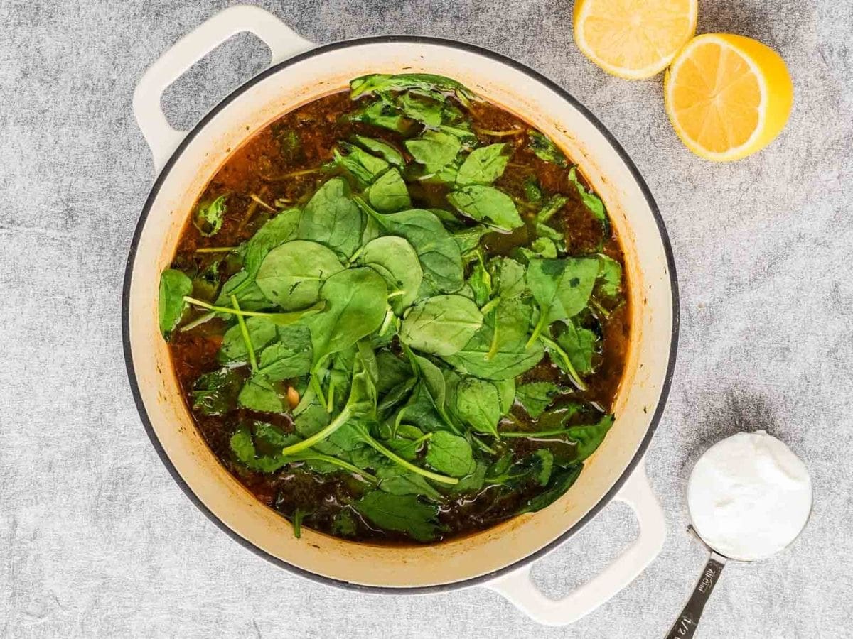 Adding the spinach to the marry me chicken soup in a pot.