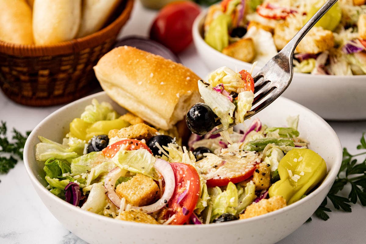 A fork, removing a bite of the dressed salad.