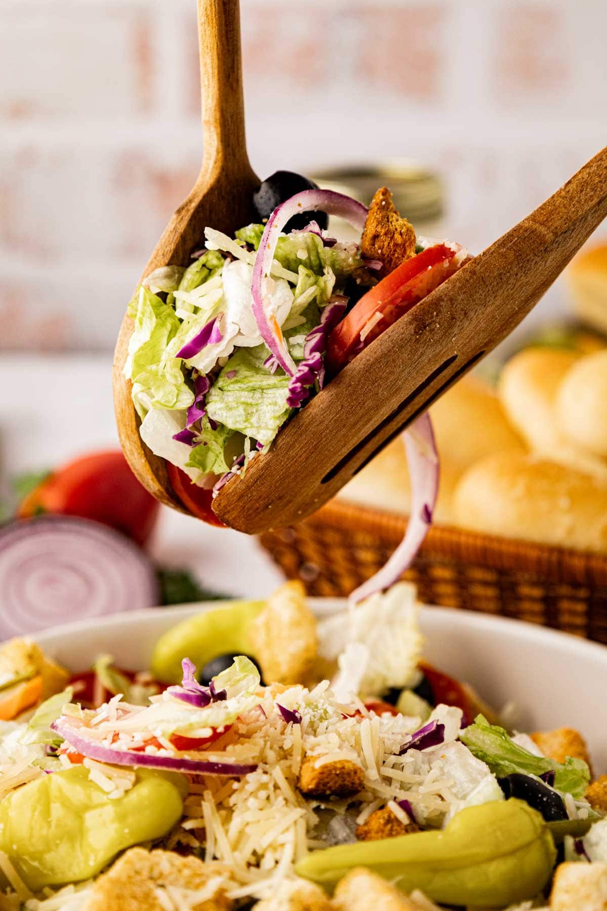 Wooden tongs, tossing the salad to coat with dressing.