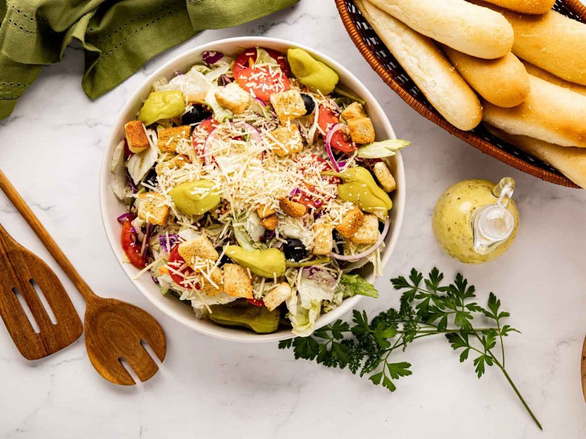 Topping the salad with cheese, pepperoncini, and croutons