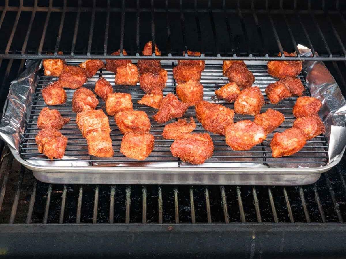 Placing the seasoned pork belly on a wire rack lined sheet pan into the smoker.