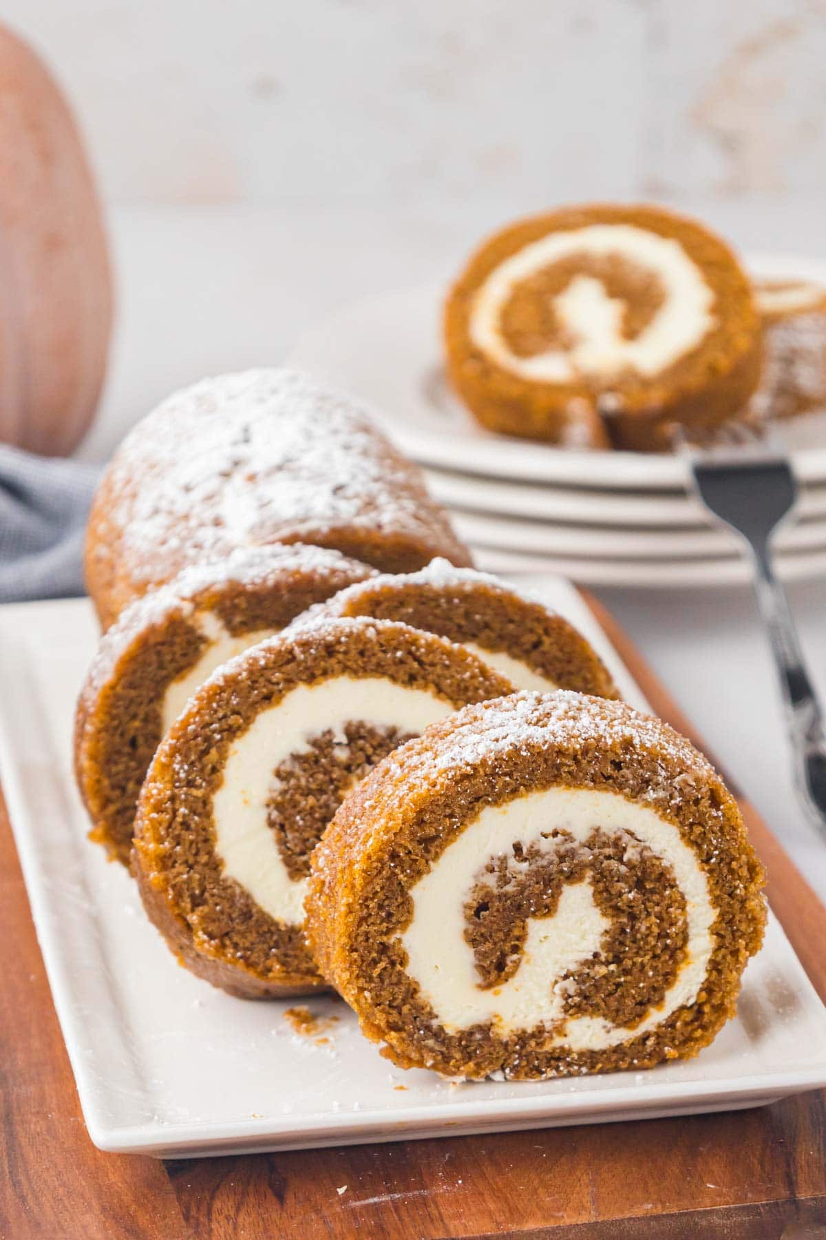 A sliced pumpkin roll on a white platter.