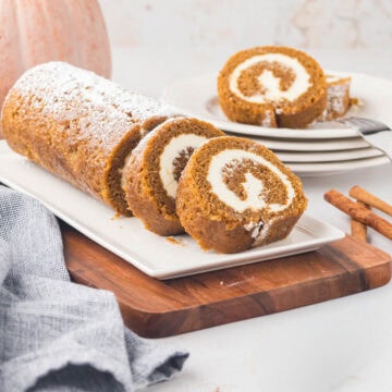 A classic pumpkin roll cake served on a rectangular cake platter.