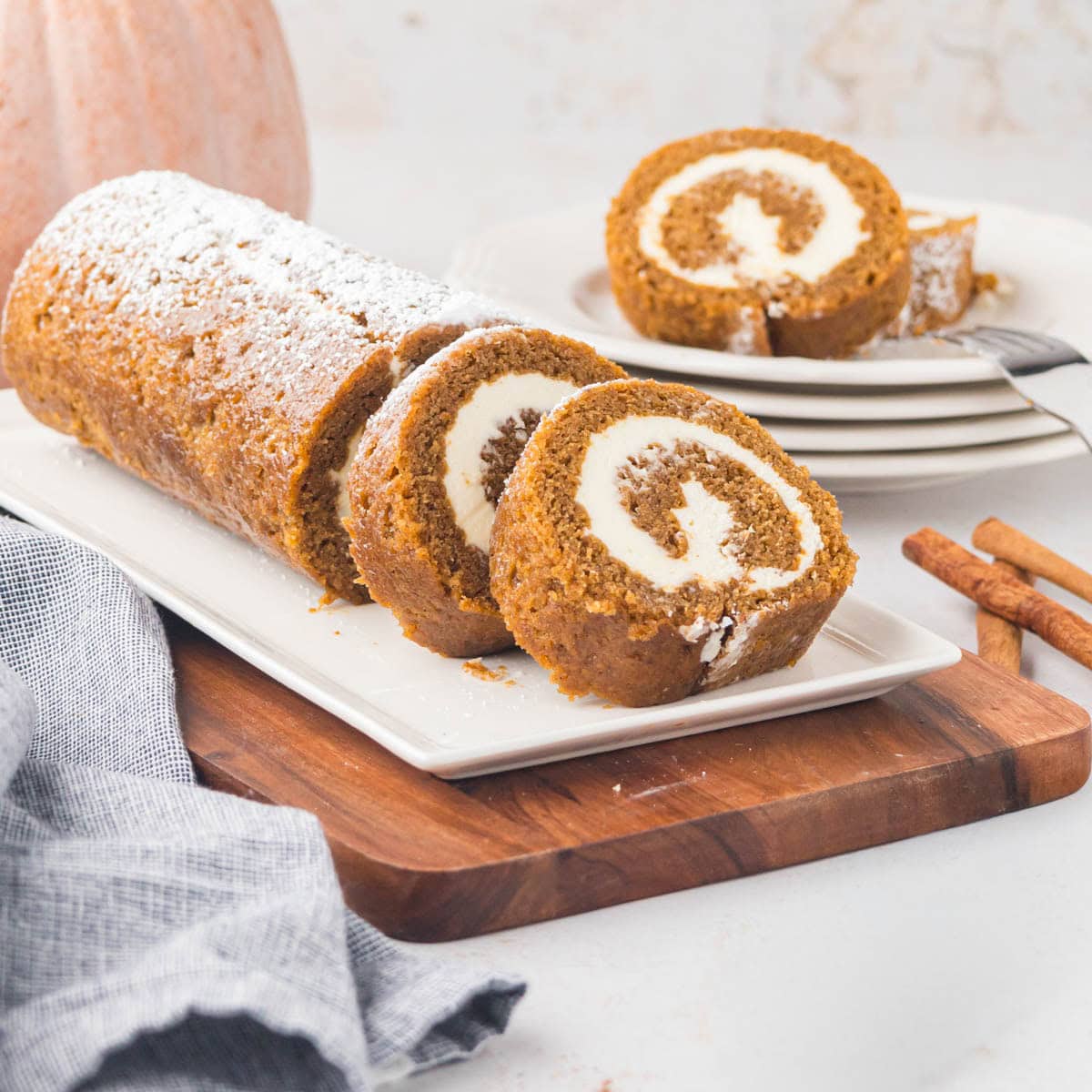 A classic pumpkin roll cake served on a rectangular cake platter.