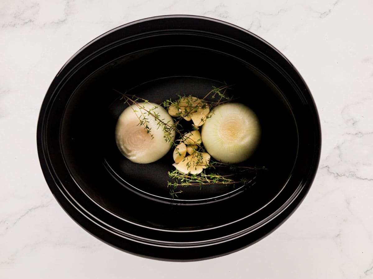 Garlic, onion and thyme sprigs added to the crockpot.