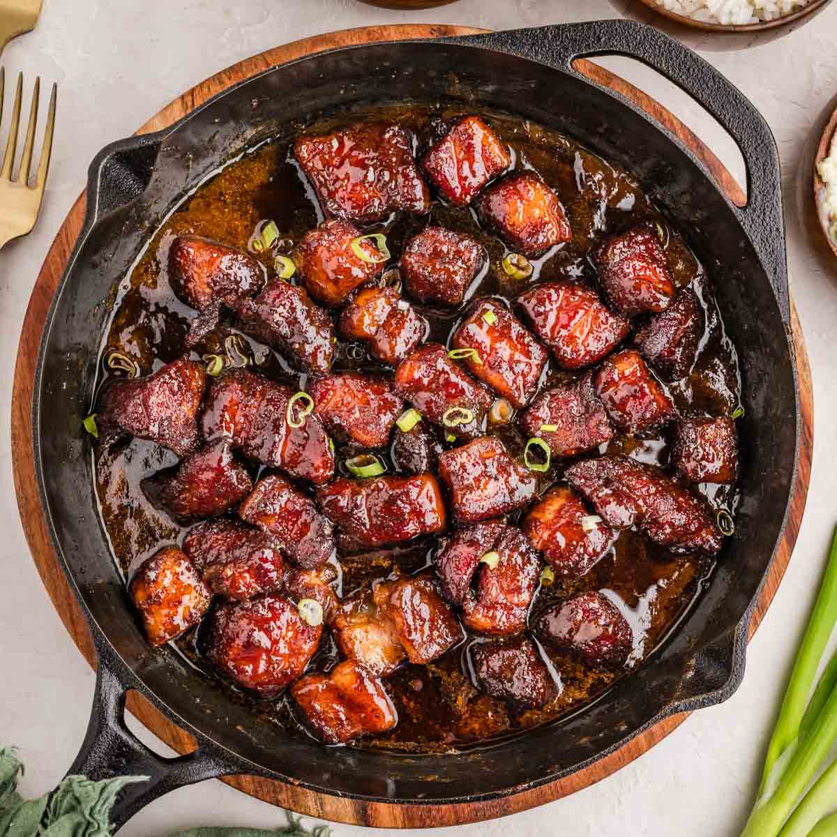 Overhead shot of smoked pork belly burnt ends in a cast iron skillet.