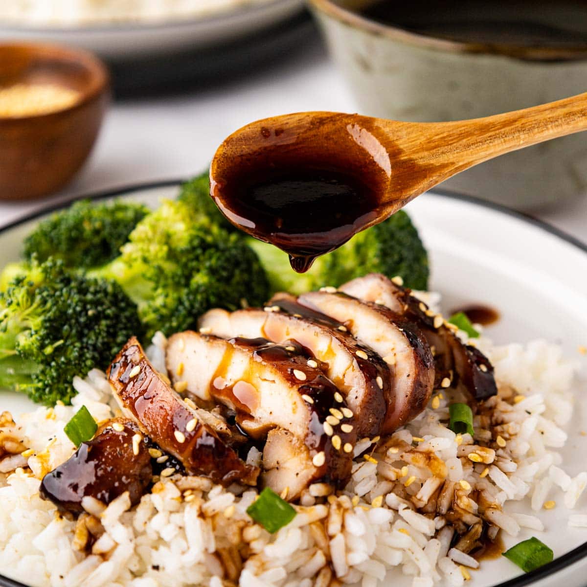 Spooning teriyaki sauce over teriyaki chicken.