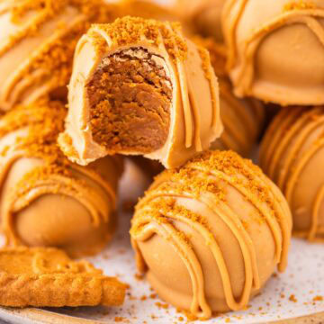 A biscoff truffle with a bite taken out and the cookie butter filling showing.