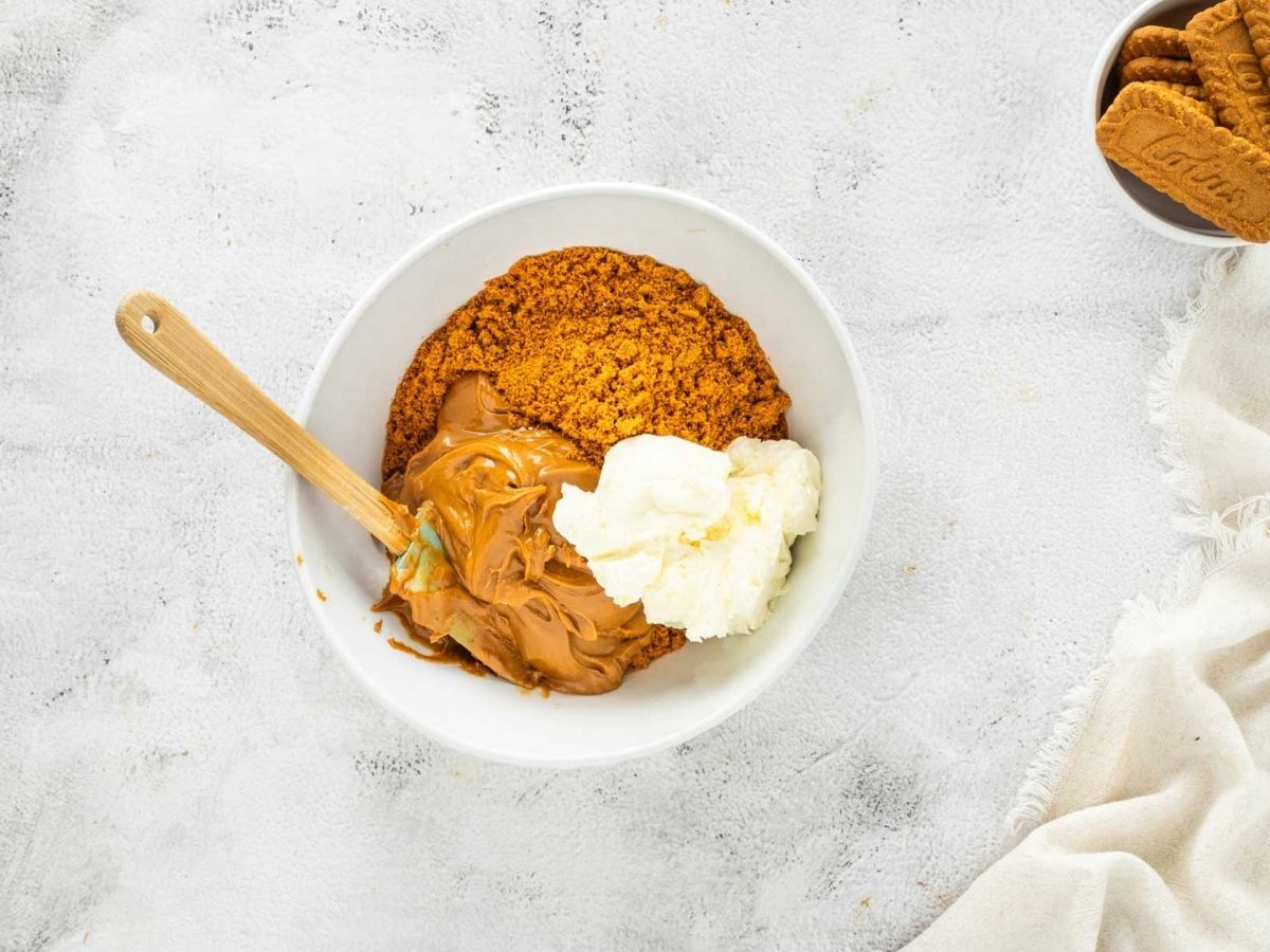 Biscoff cookie crumbs, cookie butter, and cream cheese in a bowl.