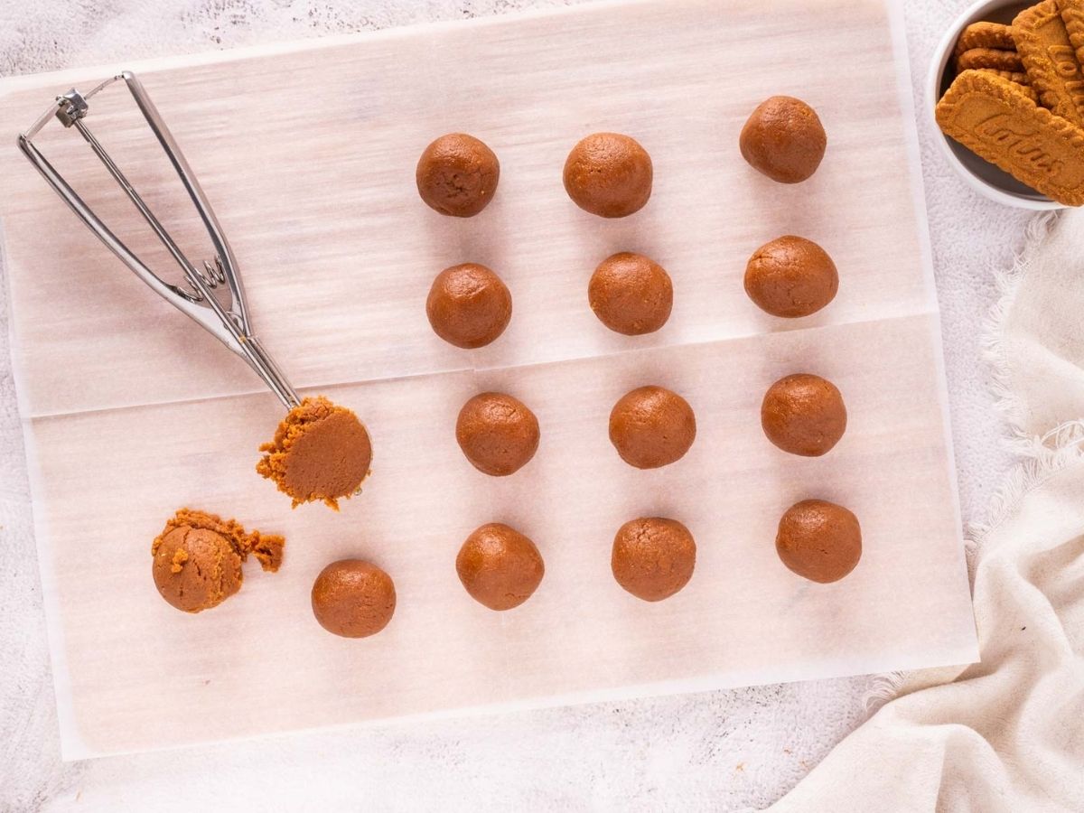 Biscoff truffle balls next to a cookie dough scoop with some of the truffle mixture in it.