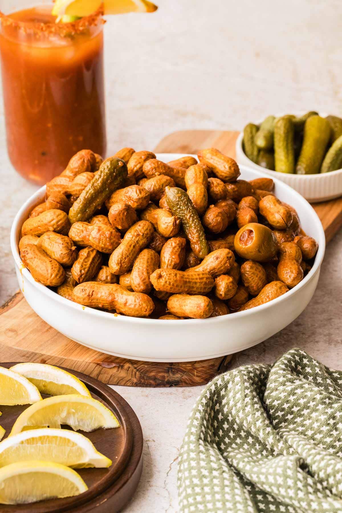 A bowl of bloody mary boiled peanuts set on a wooden board.