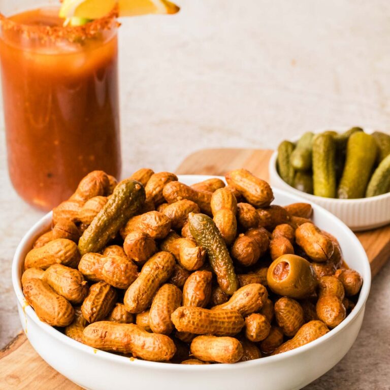 A bowl of bloody mary boiled peanuts set on a wooden board.