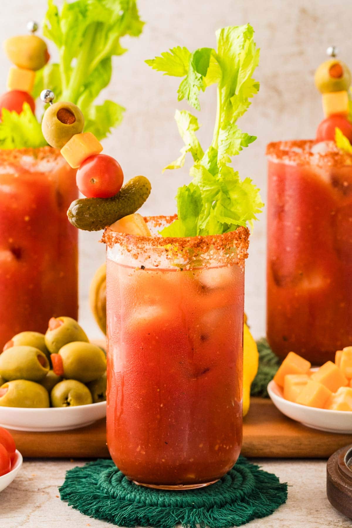Three bloody marys in glasses with garnish.
