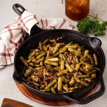 Bacon brown sugar green beans with soy sauce served in a cast iron skillet.