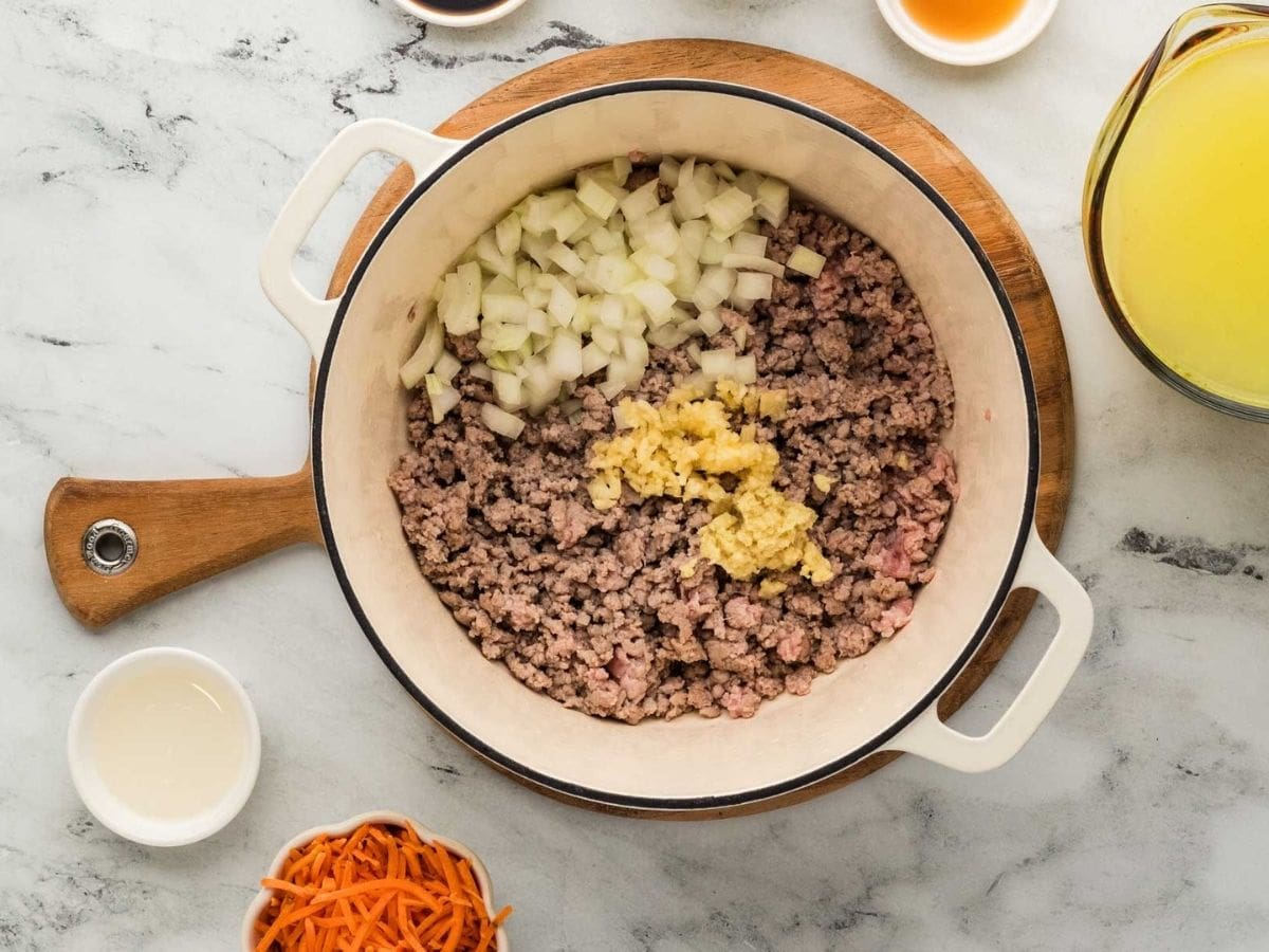 Ground pork, onion and garlic cooking in a Dutch oven pot.