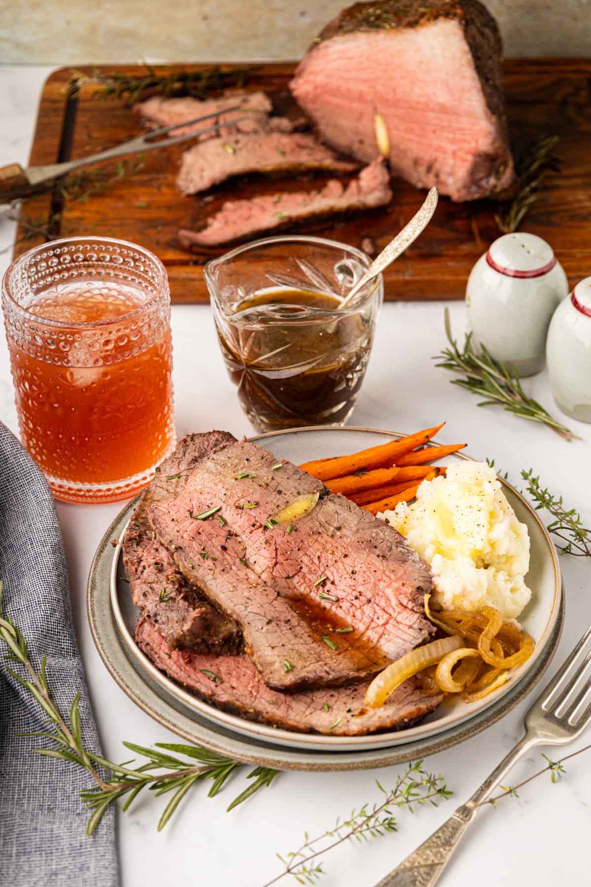 Sliced roast beef topped with au jus served with mashed potatoes and baby carrots.