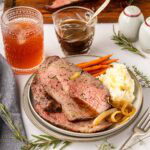 Sliced roast beef topped with au jus served with mashed potatoes and baby carrots.