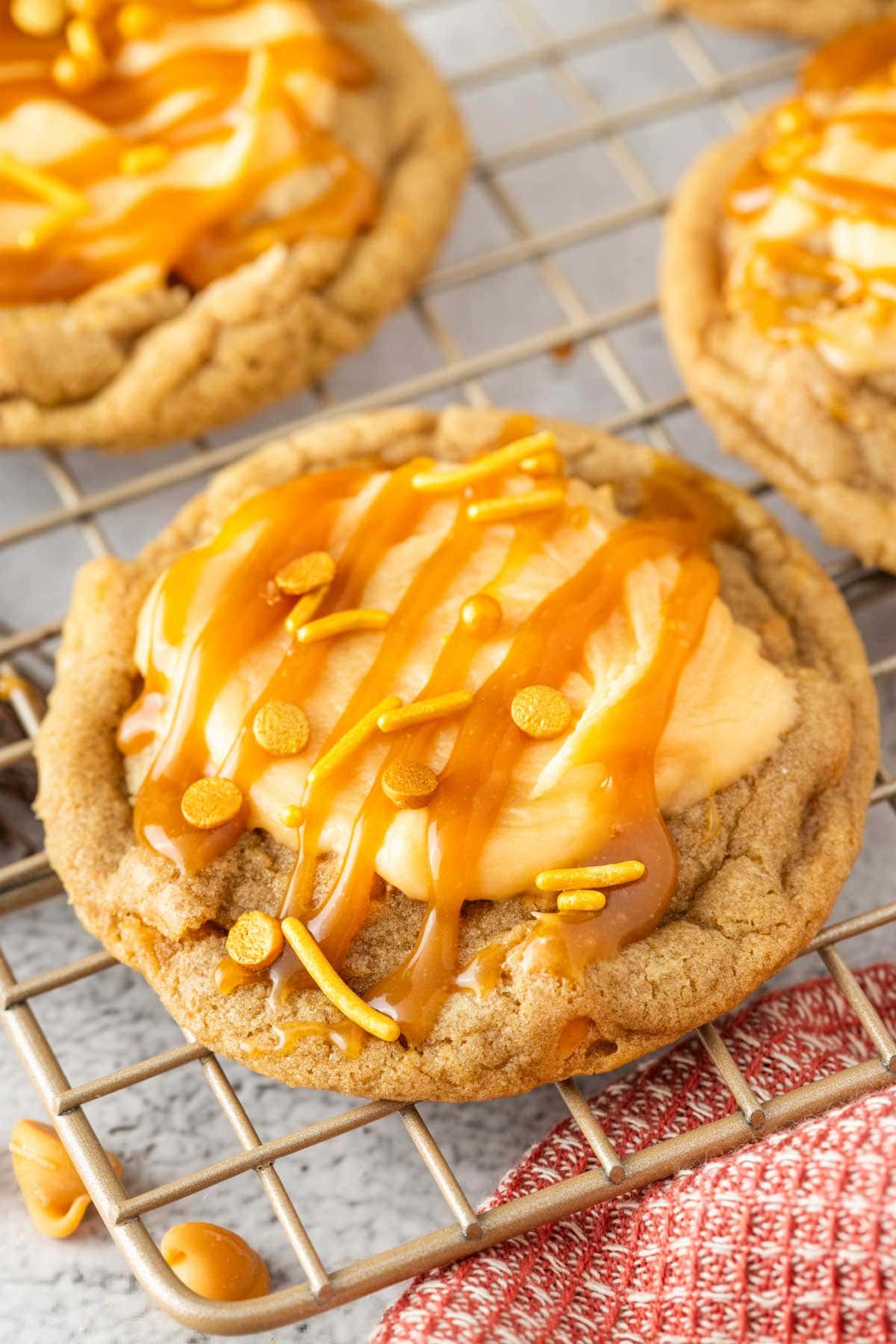 Close up of a Harry Potter butterbeer cookie on a wire rack with frosting, caramel and sprinkles on top.