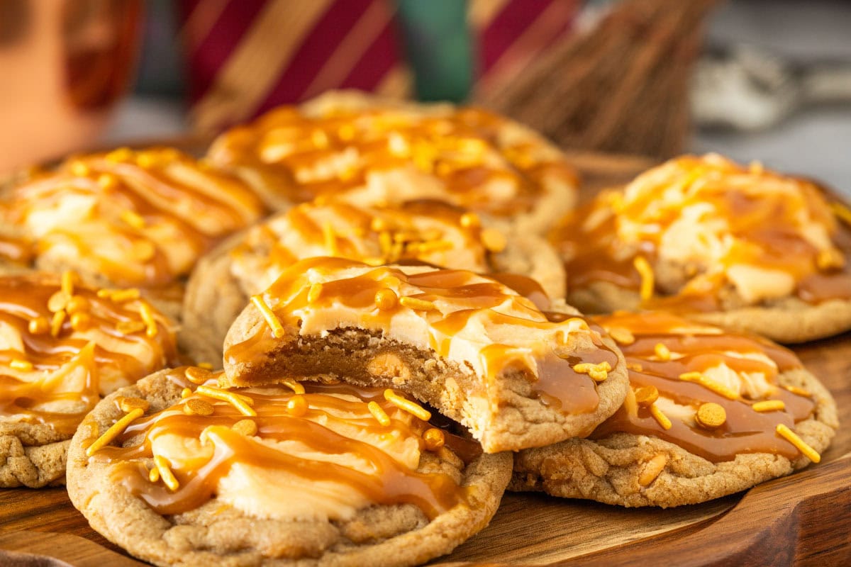 Harry Potter butterbeer cookies on a wooden platter with one cookie with a bite taken from it.