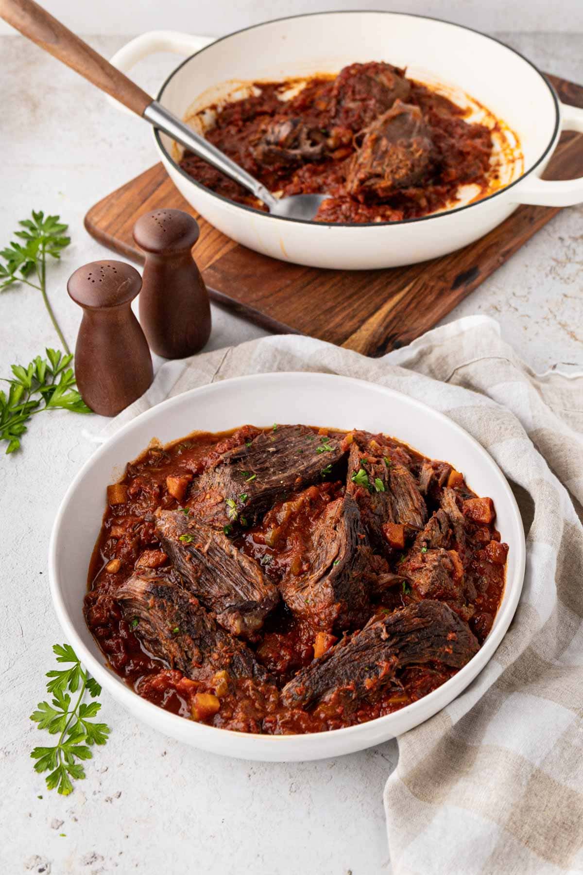 Bowl of Italian pot roast next to the Dutch oven of more pot roast.