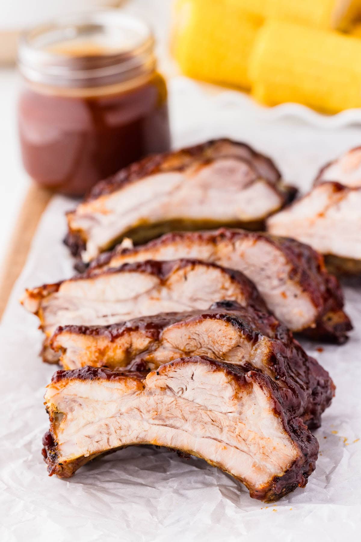 Sliced bbq ribs with bbq sauce in the background.