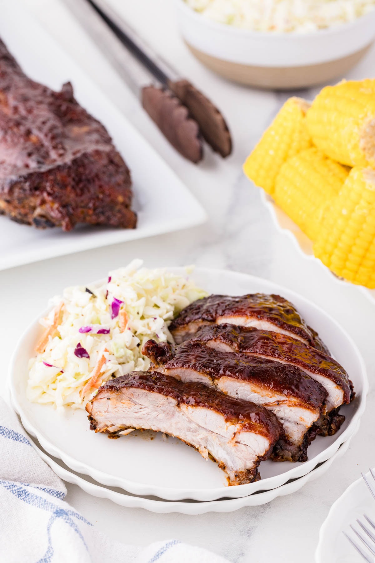 Oven baked ribs on a white plate served with coleslaw.