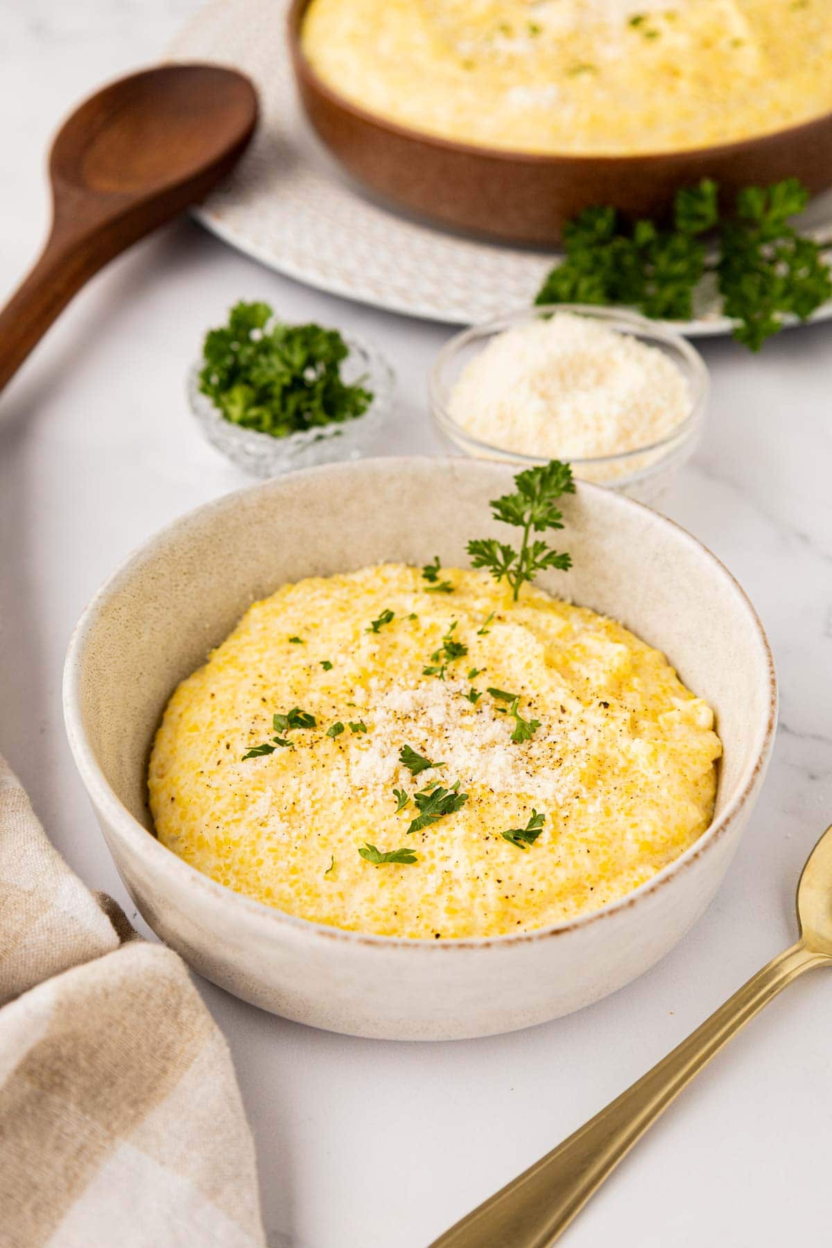 Parmesan polenta served in a bowl topped with grated parmesan cheese and parsley.