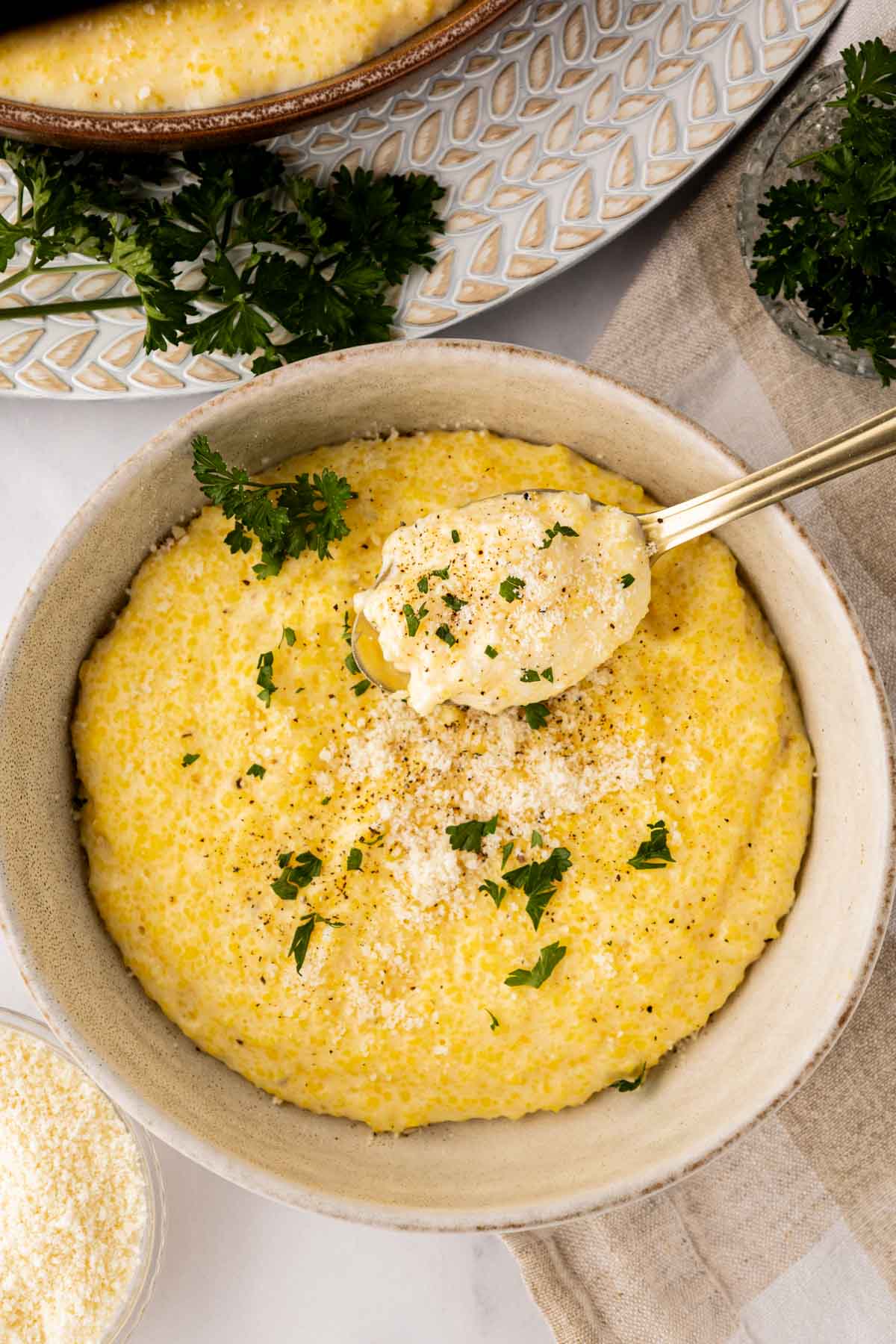 Parmesan polenta in a bowl with a spoon taking a bite.