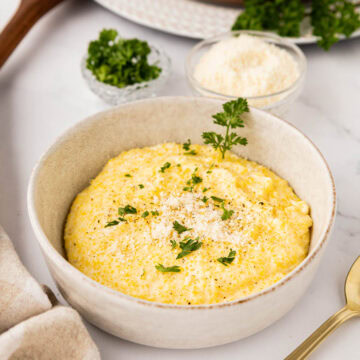 Creamy parmesan polenta in a bowl garnished with parsley.