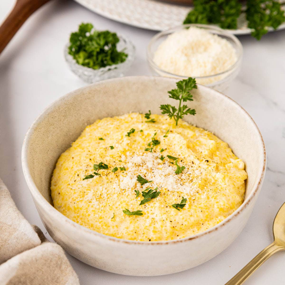 Creamy parmesan polenta in a bowl garnished with parsley.