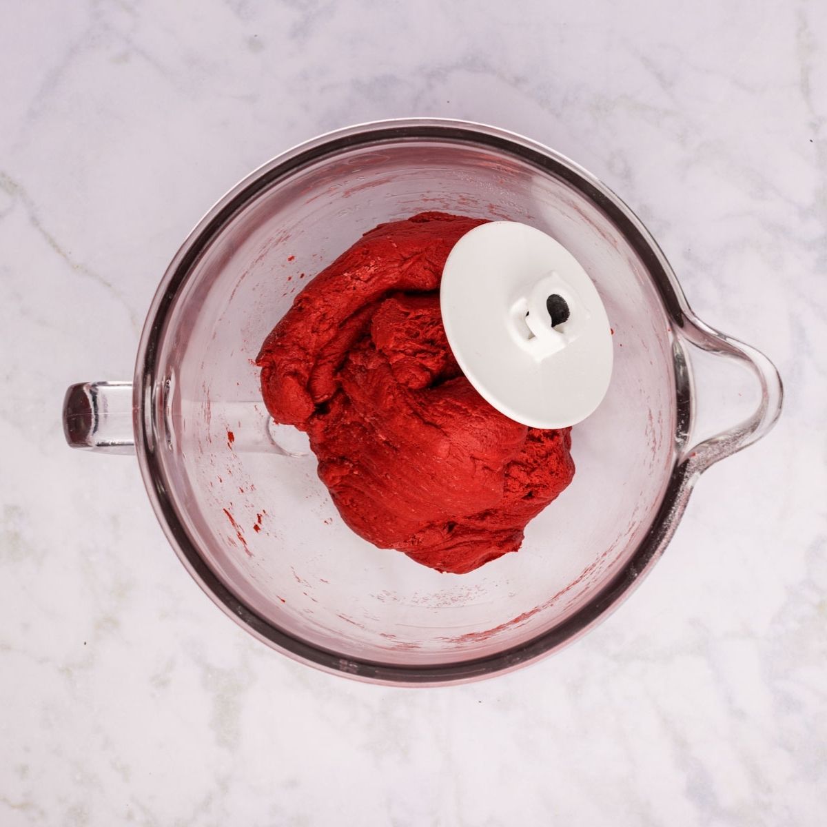 Red velvet cinnamon roll dough in a bowl with the dough hook.
