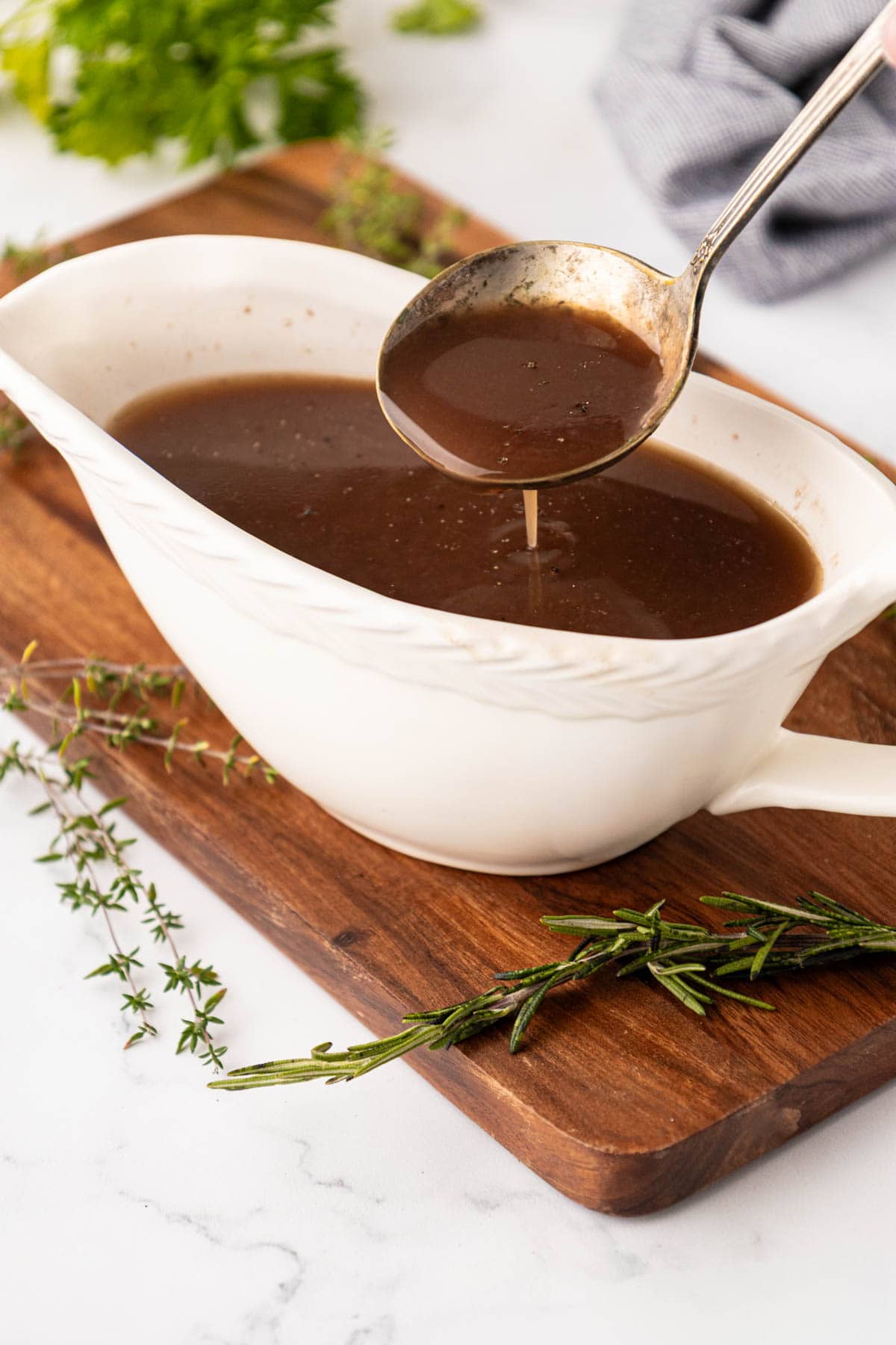 A small gravy ladle, removing a serving of beef Aji from a white bowl.
