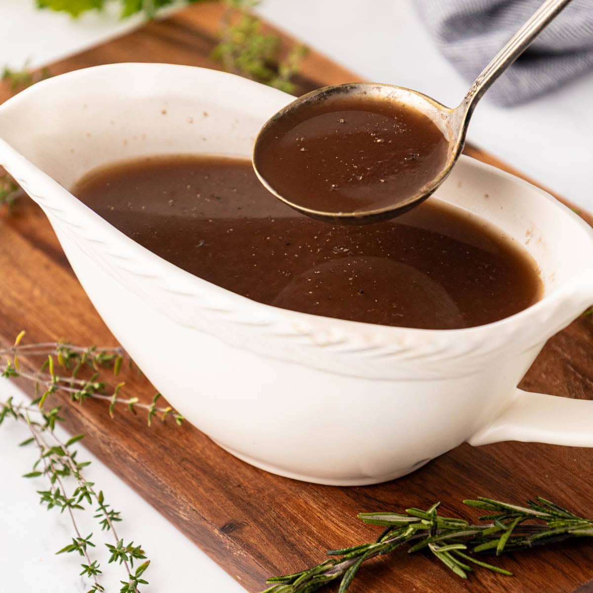 A juice sauce, garnished with cracked pepper on top in a white bowl.