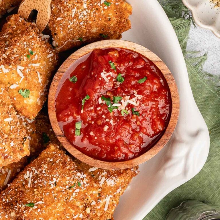 A bowl of calabrian sauce with toasted ravioli.