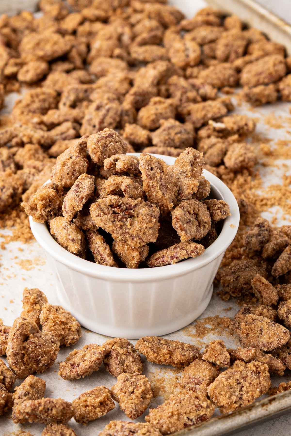 Candy pecans in a white bowl set on a tray.