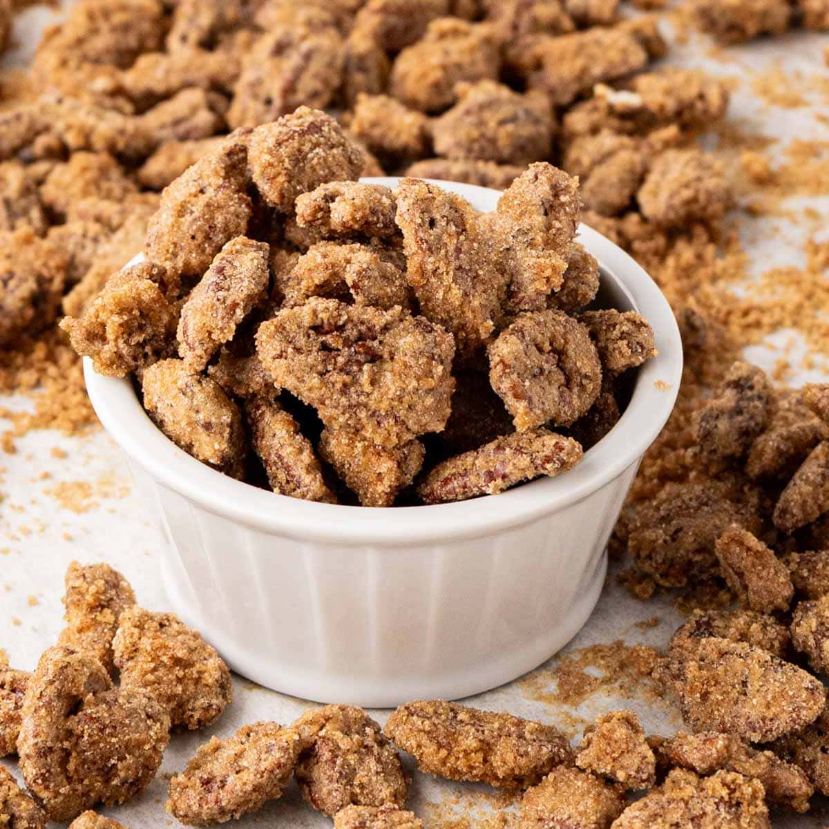 Candied pecans in a white bowl set on a tray.
