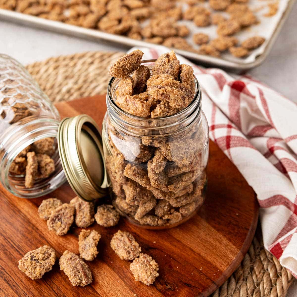 Praline pecans in a mason jar on a wooden board.