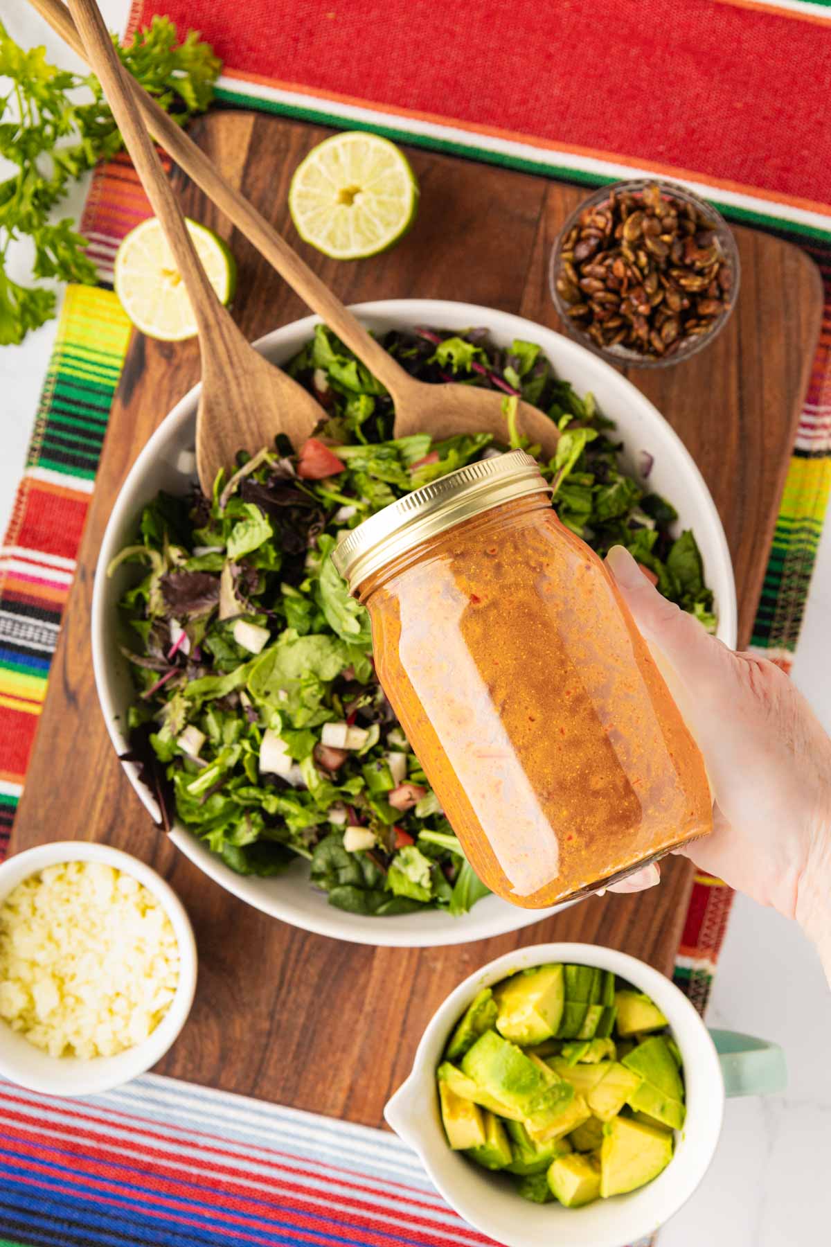 Shaking the mason jar with the chipotle vinaigrette in it with a salad bowl in the background.