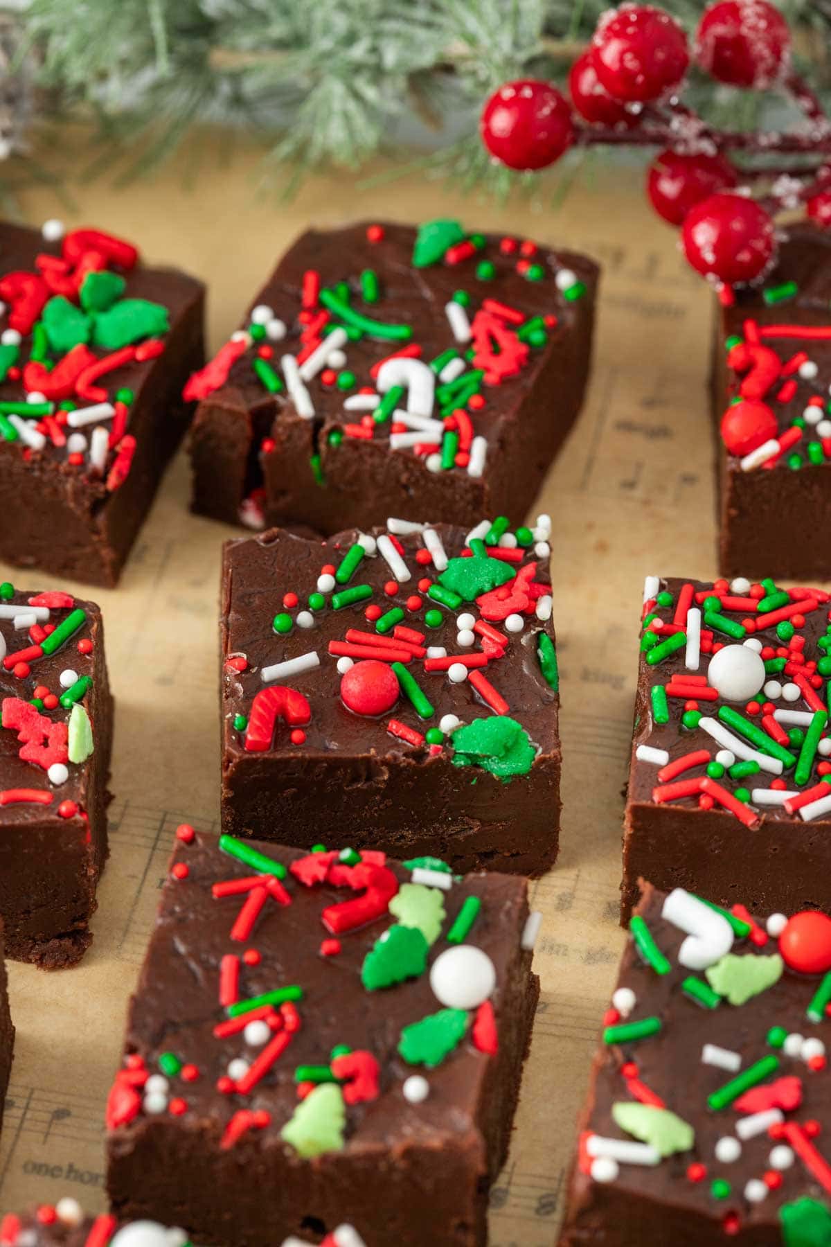 Squares of Christmas fudge lined up with some Christmas decorations in the background.