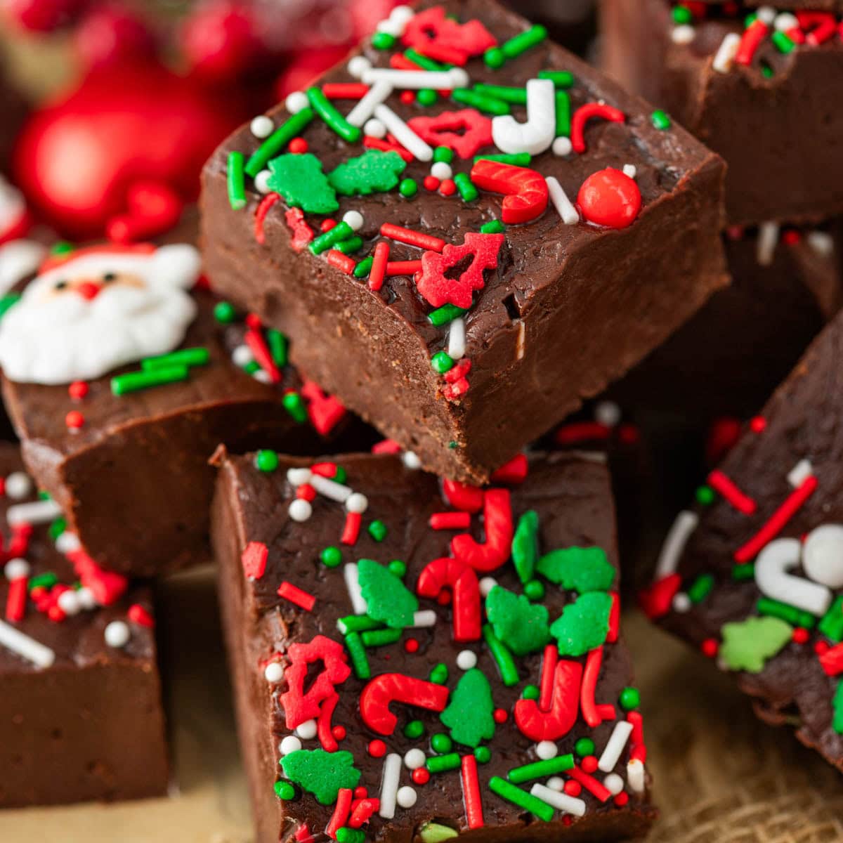 Pieces of Christmas fudge with holiday sprinkles stacked on top of each other.