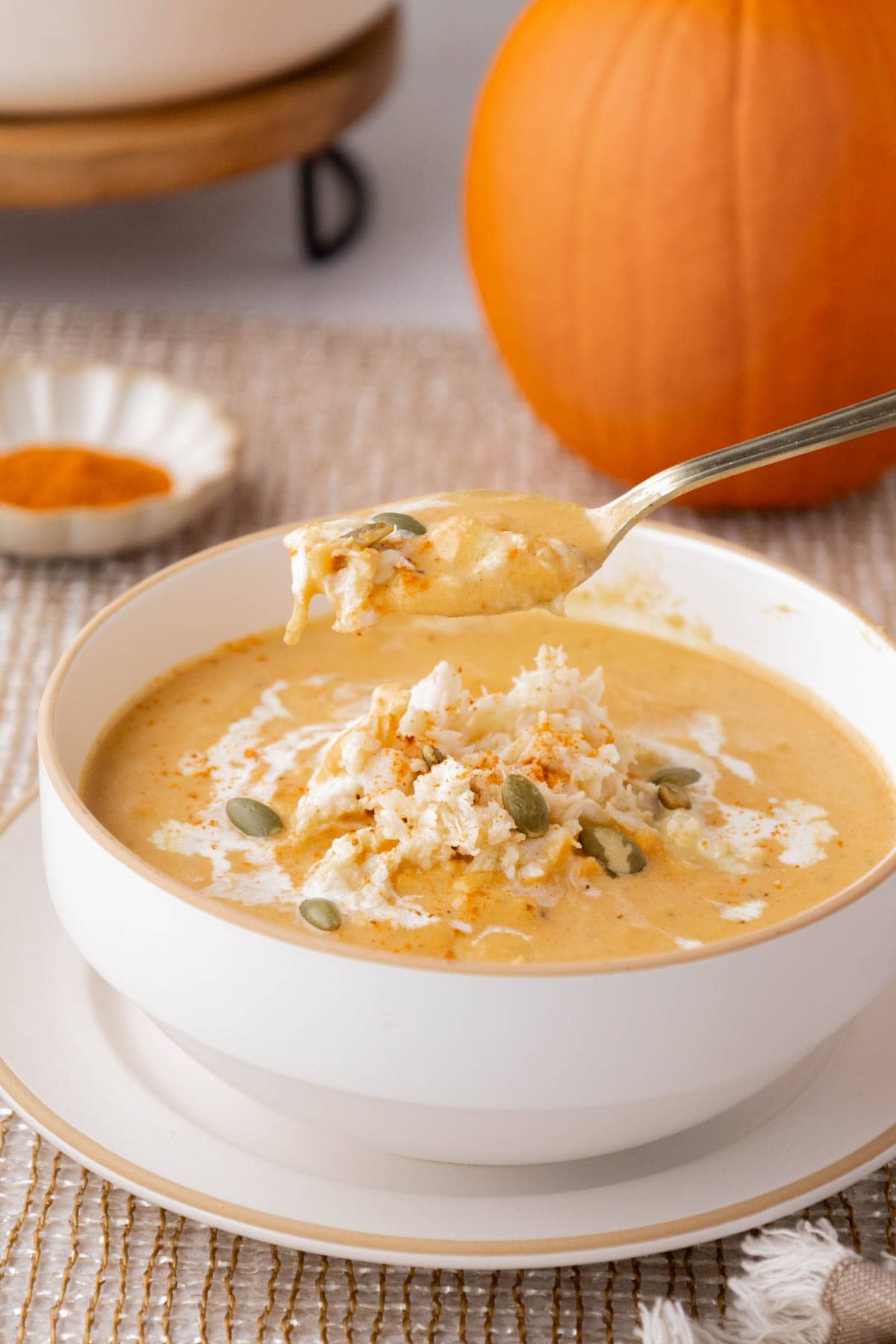 A spoon removing a bit of pumpkin crab bisque.